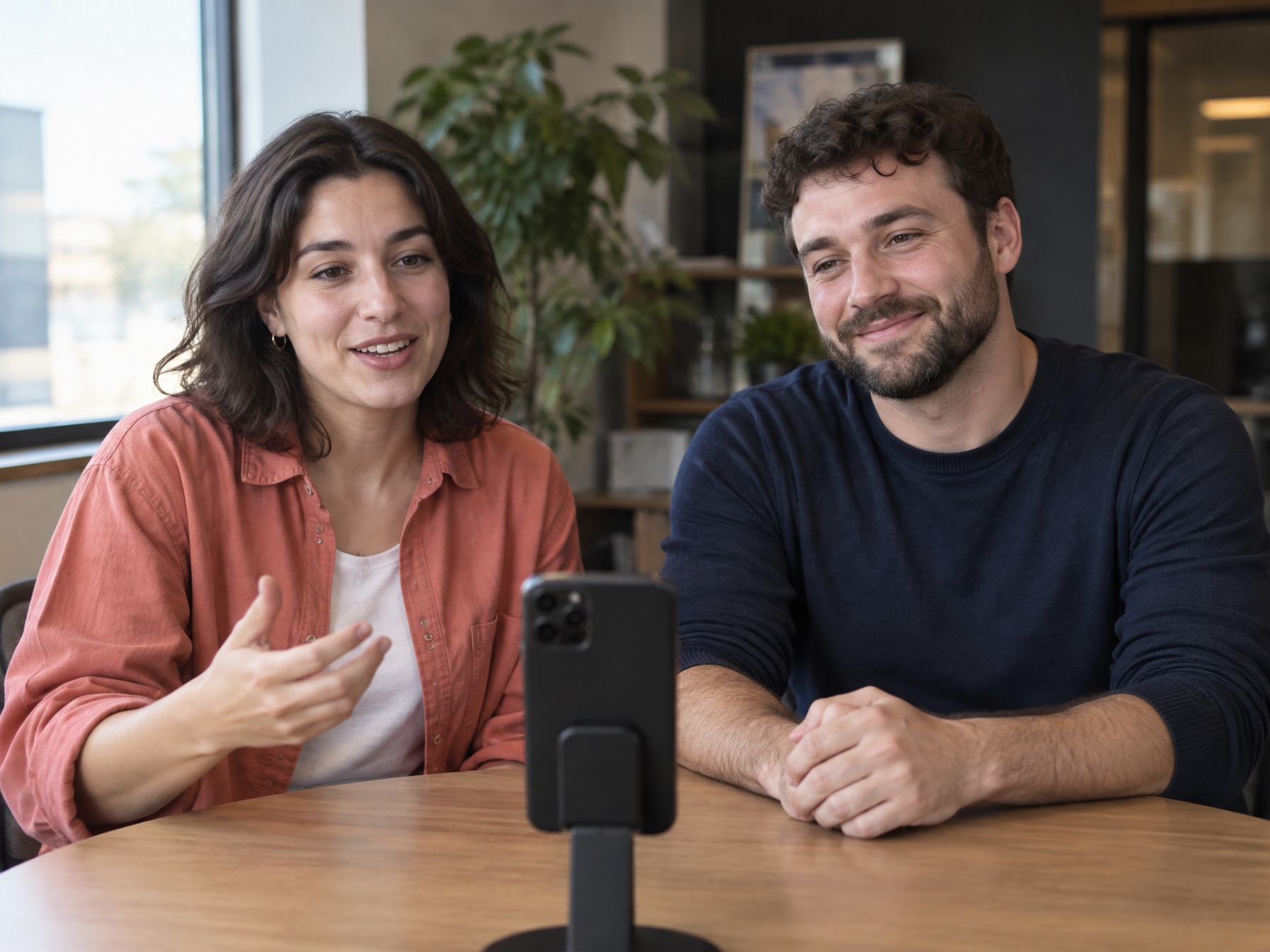 Two coworkers recording a thank-you message on a phone